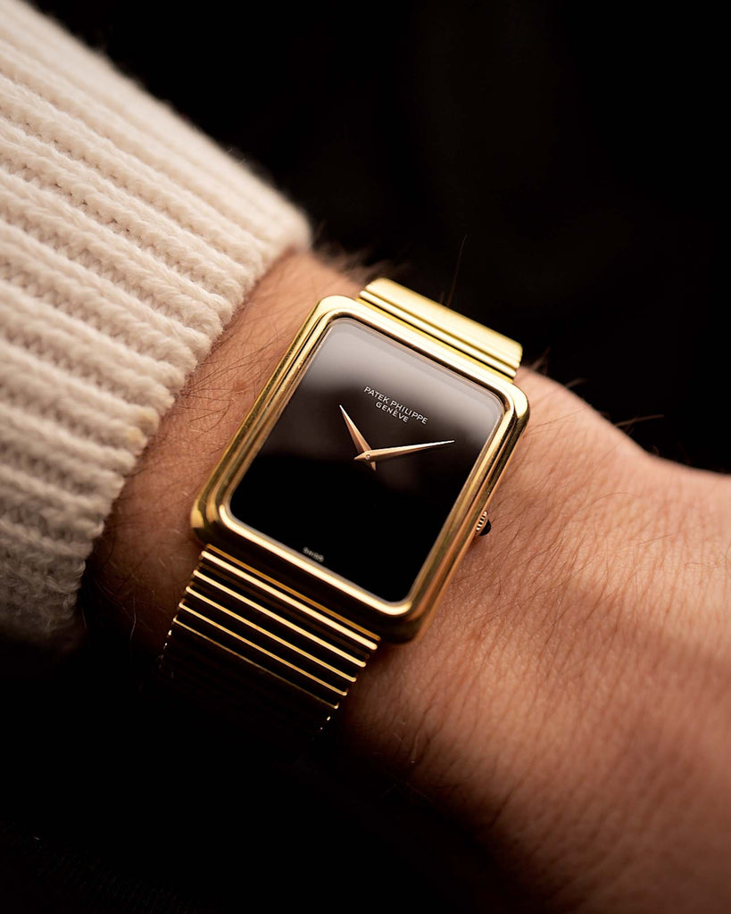 Reloj vintage Patek Philippe 3649 Jumbo de 1977, caja de oro amarillo de 18 quilates, esfera de ónix negro, movimiento manual, en una muñeca sobre fondo negro, vídeo.