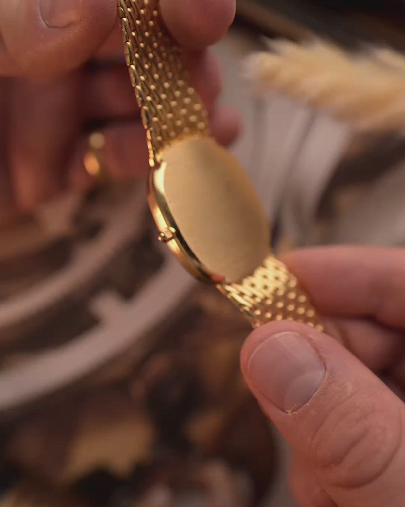 Close-ups of a Patek Philippe 3738 Ellipse Jumbo Vintage Watch from the 1980s on a blurred background. 31mm wide with 18k Yellow Gold Case, Automatic Caliber 240, Flawless Blue Sunburst Sigma Dial and Yellow Gold Bracelet.