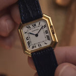 Reloj vintage Cartier Ceinture 78099 con caja cuadrada de oro amarillo de 18 quilates, esfera blanca, cuerda manual, correa de cuero azul sobre fondo difuminado, vídeo con detalles.