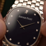 Gros plan sur une montre Audemars Piguet Cobra vintage, or blanc 18 carats, cadran en diamants bleu nuit, mouvement manuel, bracelet intégré, fond flou