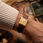 Montre vintage Audemars Piguet Square, or 18k, cadran satiné doré, bracelet en cuir, au poignet, fond flou