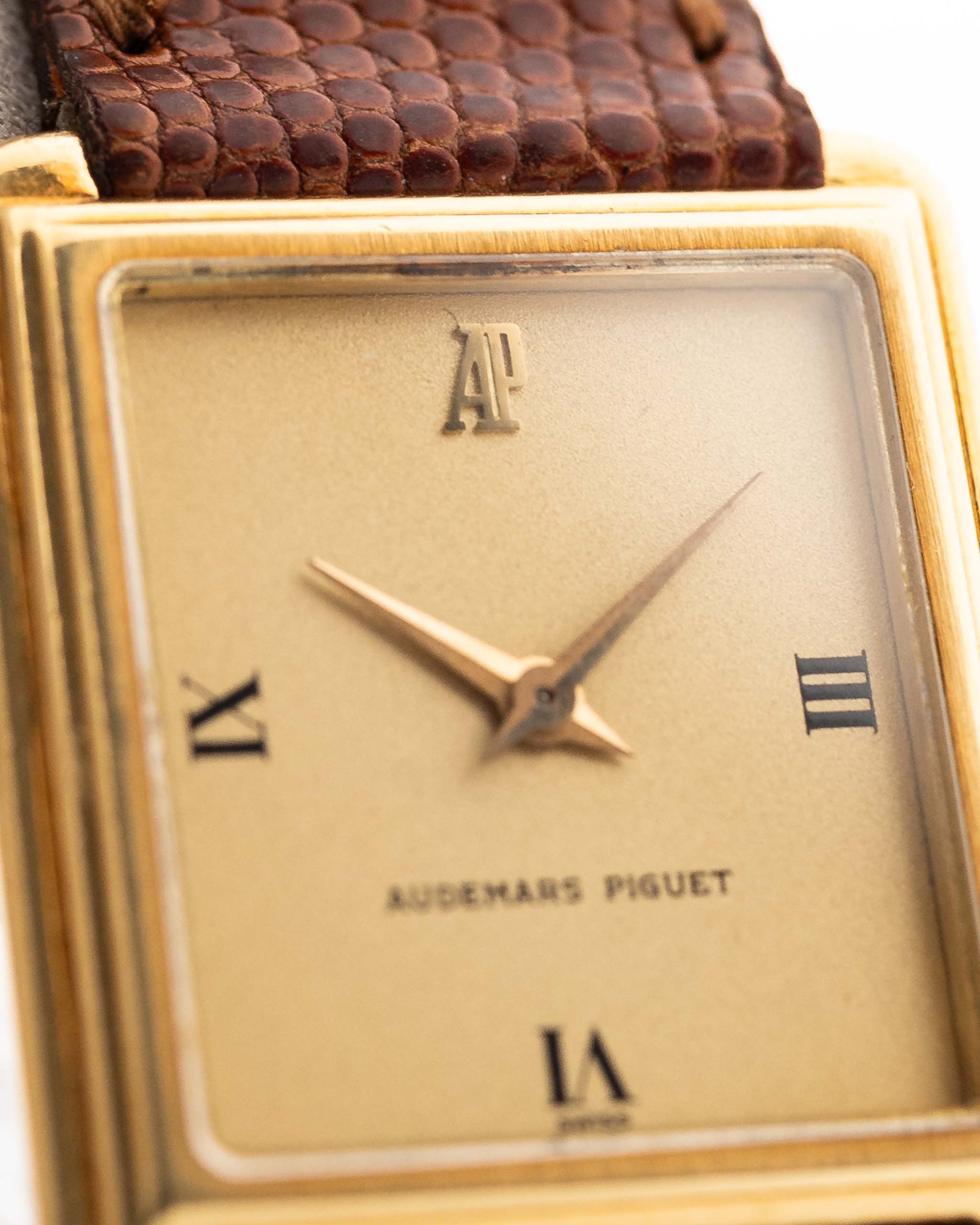 Gros plan d'une montre Vintage Audemars Piguet Square, or 18k, cadran satiné doré, bracelet en cuir, fond blanc