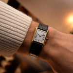 Montre Cartier Tank Louis vintage, or jaune 18 carats, cadran blanc, mouvement manuel, sur bracelet en alligator noir, au poignet, fond flou