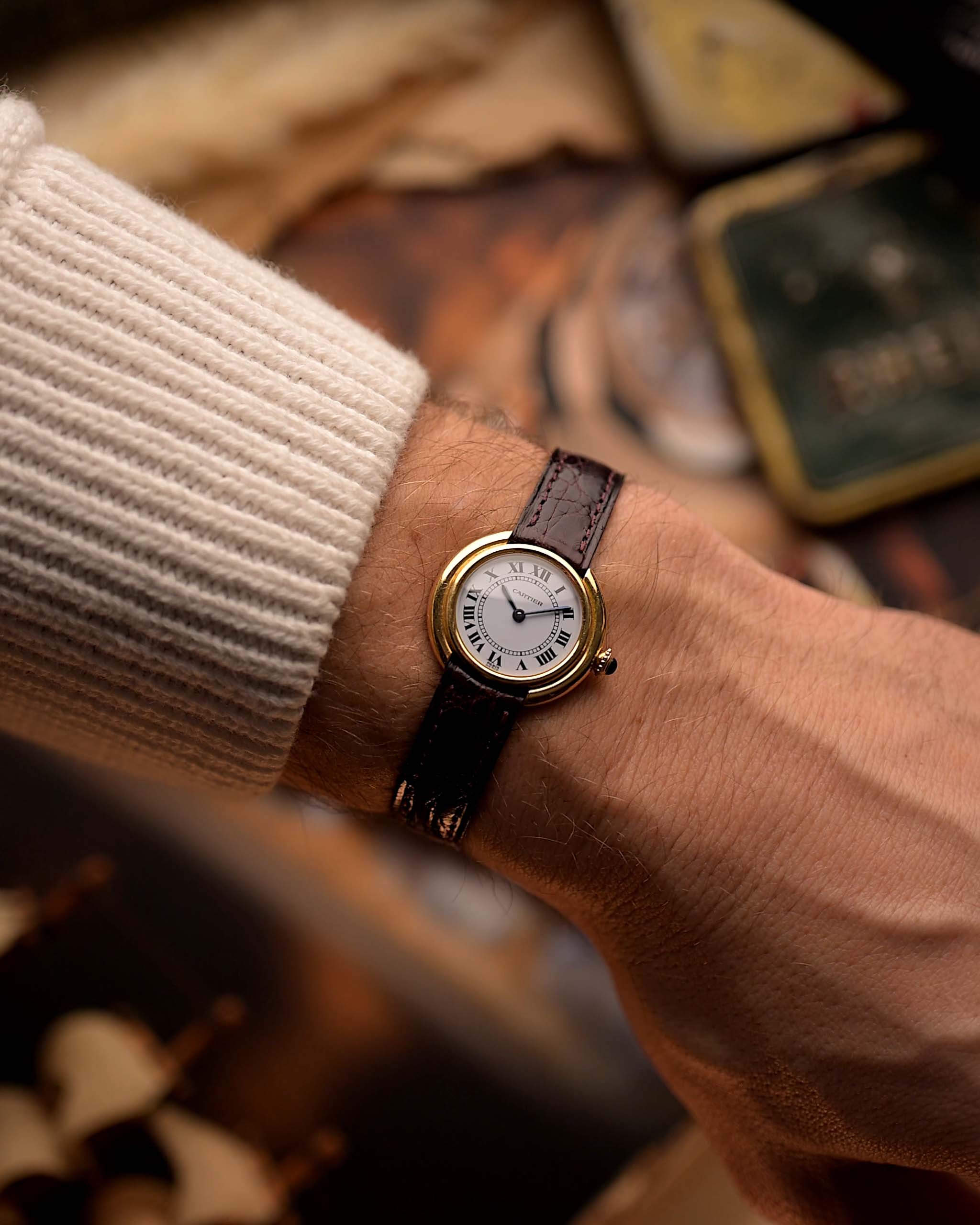 Montre Vintage Cartier Ellipse en or 18k, cadran blanc, signature Paris, bracelet original en cuir rouge, au poignet, fond flou