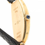 Photo en gros plan d'une Cartier Tonneau 18k Guilloché Paris des années 1980. 39mm avec boîtier en or jaune 18k, mouvement à remontage manuel, cadran Guilloché Paris original et bracelet en cuir noir.