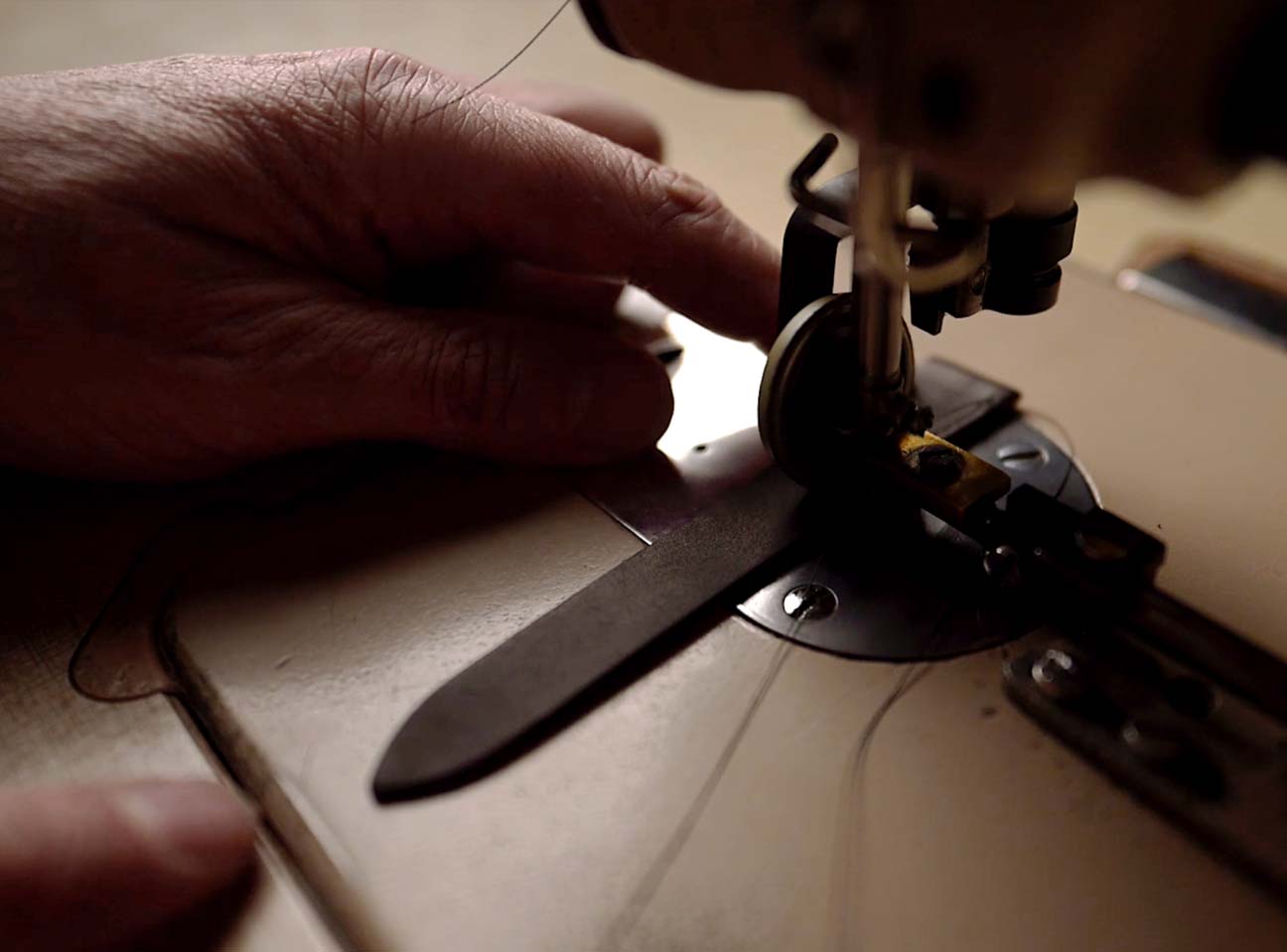 Guidage à la main du bracelet de montre en cuir sous la machine à coudre.