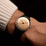 Montre Omega Medicus Salmon Roman de 1944 au poignet. 28 mm, acier inoxydable, calibre 23.4 SC à remontage manuel, cadran saumon impeccable, chiffres romains et bracelet en cuir noir.