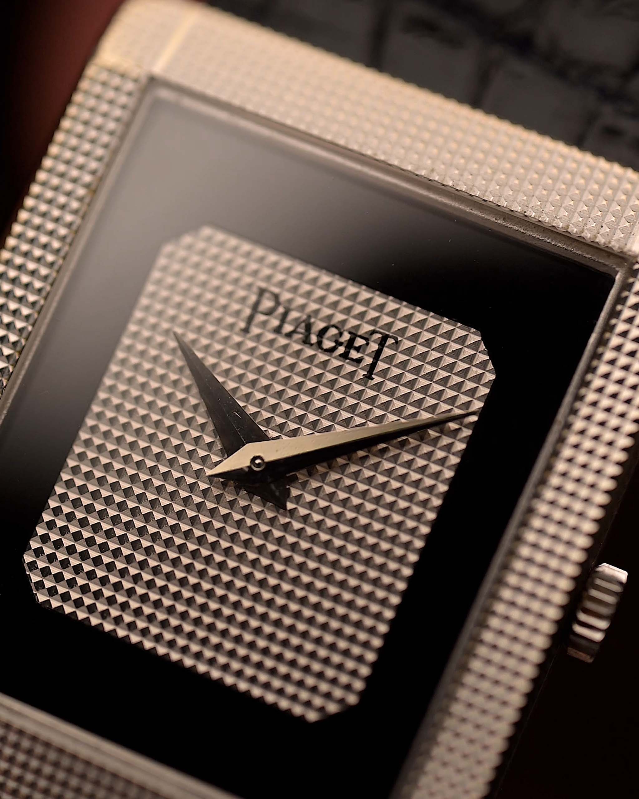 Gros plan d'une montre Piaget Protocole 9151 de collection, or blanc 18 carats, cadran Onyx, forme tank, mouvement Calibre 9P, bracelet en cuir, sur un poignet, fond flou