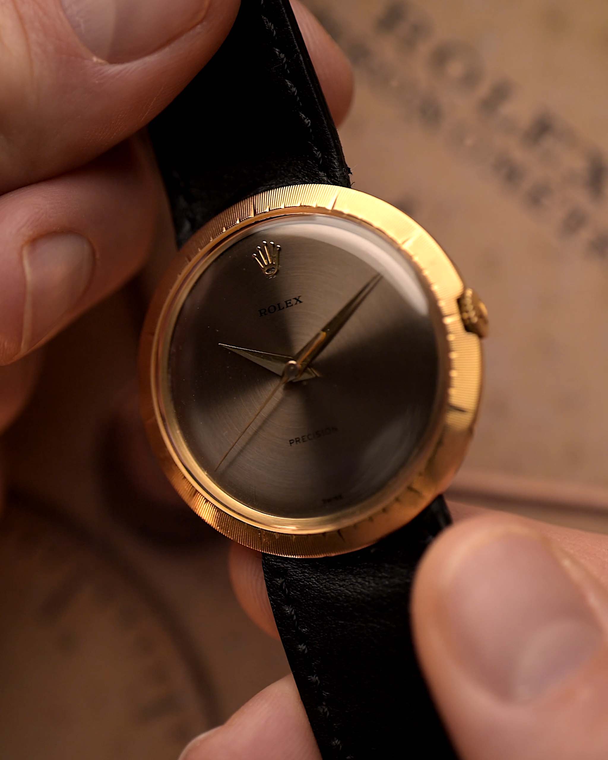 Montre vintage Rolex Precision 9919 tenue par une main sur un fond flou