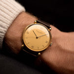 Montre Omega Medicus Salmon Roman de 1944 au poignet. 28 mm, acier inoxydable, calibre 23.4 SC à remontage manuel, cadran saumon impeccable, chiffres romains et bracelet en cuir noir.