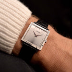 Montre Piaget Protocole 927 en or blanc 18k des années 1970 sur un poignet. 25mm en or blanc 18k avec mouvement à remontage manuel, cadran argenté soleillé d'origine, bracelet en cuir noir d'origine, boucle en or blanc 18k.