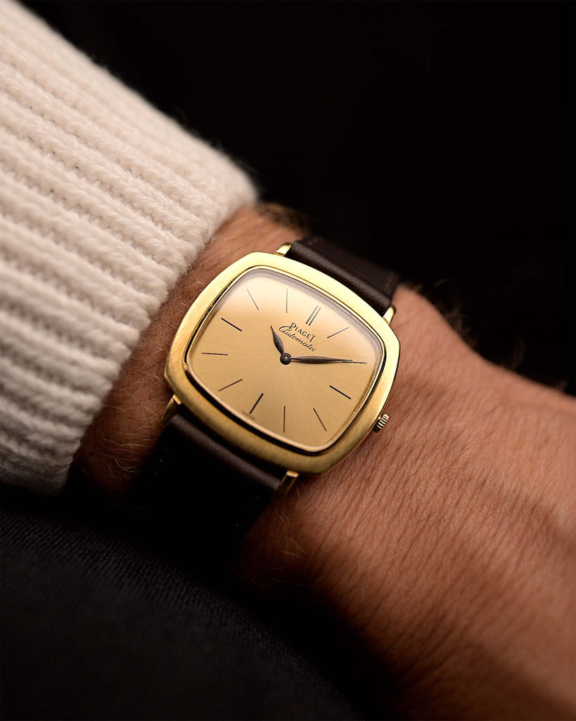 Montre vintage Piaget TV 12432 Automatic 18k des années 1970 sur un poignet. 32.5mm avec boîtier en or jaune 18k, calibre automatique 12P1, cadran doré, aiguilles en forme de feuilles et bracelet en cuir.