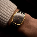 Montre vintage Vacheron Constantin 39007 Ellipse en or 18 carats, boîtier elliptique, cadran gris, remontage manuel, bracelet en cuir noir sur un poignet sur fond noir, vidéo.