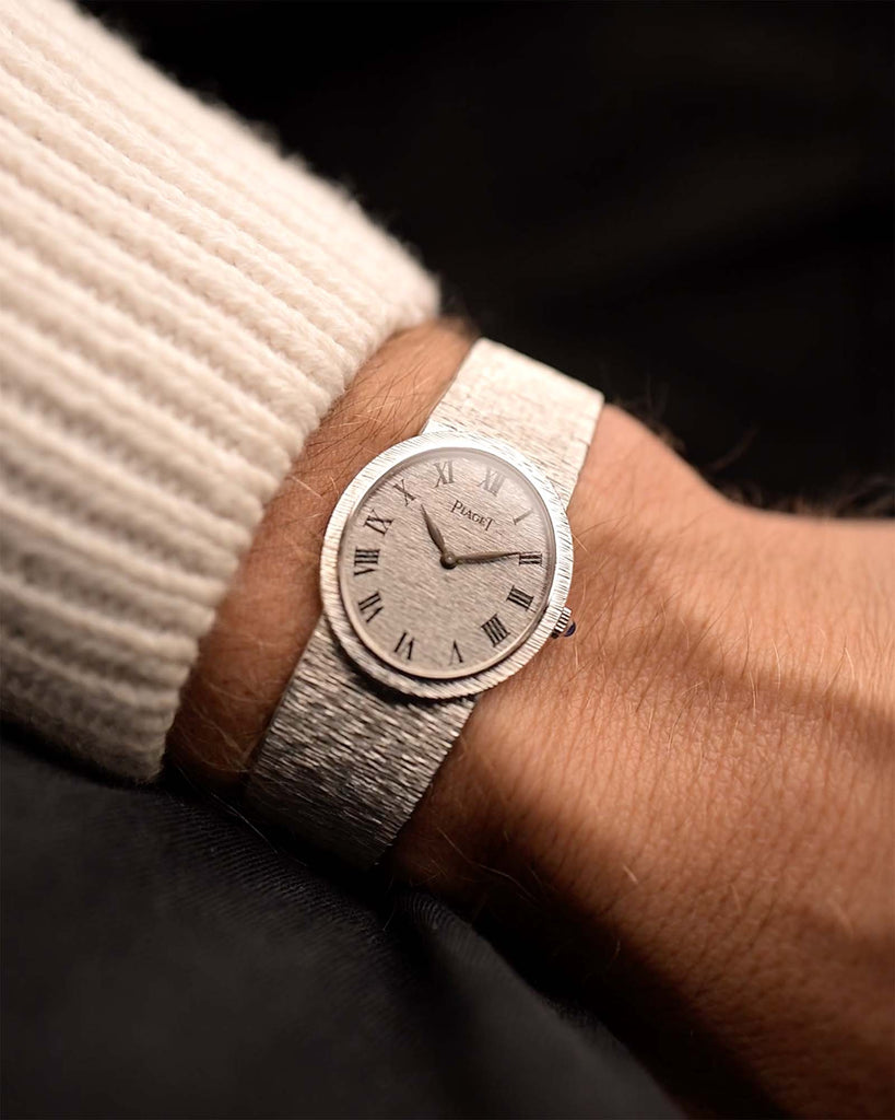 Montre Piaget Ellipse 9821 Roman 18k des années 1970 sur un poignet. 24mm en or blanc 18k avec mouvement à remontage manuel, cadran fini écorce et bracelet intégré.