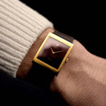 Rolex Cellini 4014 Montre Vintage de 1972 au poignet sur fond noir. Boîtier en or jaune 18 carats, 22,5 mm de large, cadran bourgogne brillant, mouvement à remontage manuel et bracelet en cuir brun foncé.