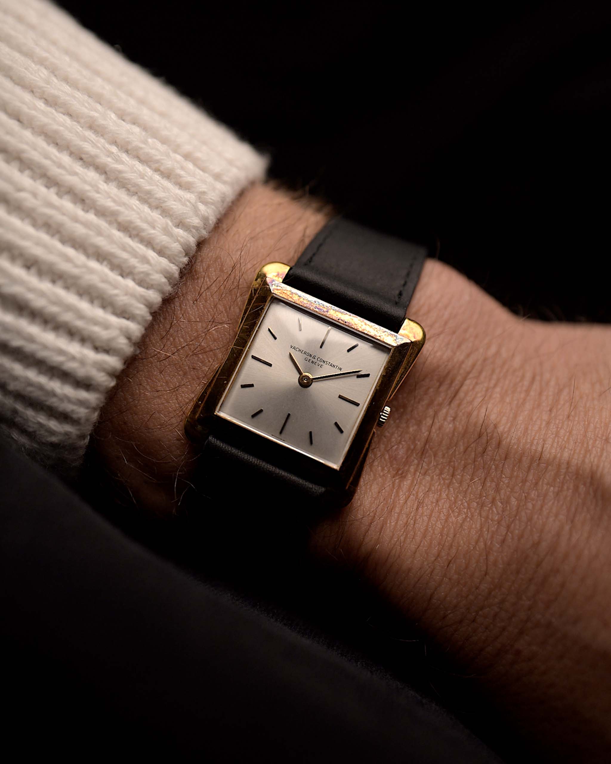 Vacheron Constantin 4963 Toledo Montre Vintage des années 1950 sur un poignet sur fond noir. Largeur 27 mm, boîtier en or jaune 18 carats, mouvement à remontage manuel, cadran argenté en forme de soleil et bracelet en cuir noir.