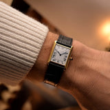 Orologio Cartier Tank Louis vintage, oro giallo 18 carati, quadrante bianco, movimento manuale, su cinturino in alligatore nero, su un polso, sfondo sfocato