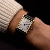 Orologio vintage Cartier Tank Louis, oro giallo 18 carati, quadrante bianco, movimento manuale, su cinturino in alligatore nero, su un polso, sfondo nero