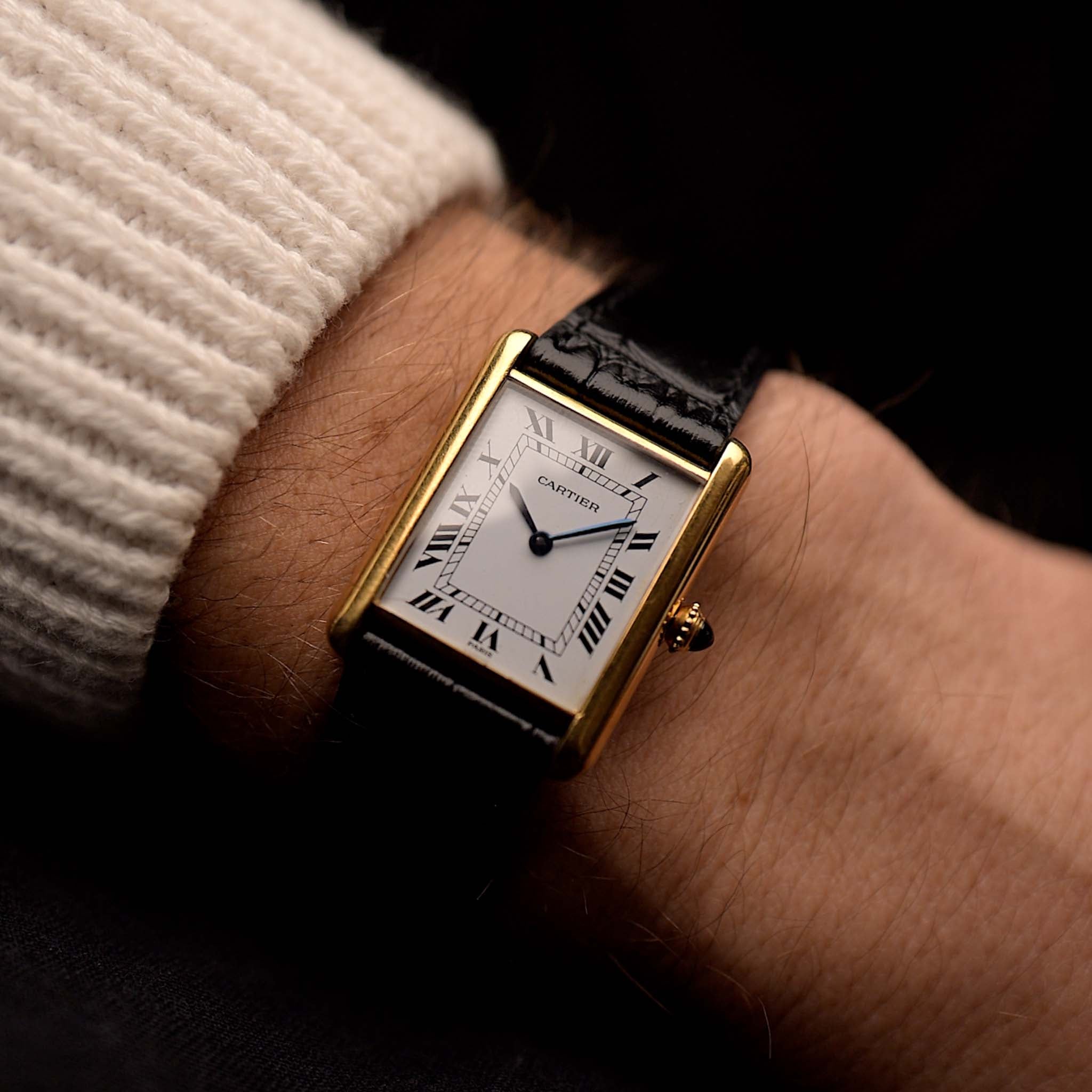 Orologio vintage Cartier Tank Louis, oro giallo 18 carati, quadrante bianco, movimento manuale, su cinturino in alligatore nero, su un polso, sfondo nero