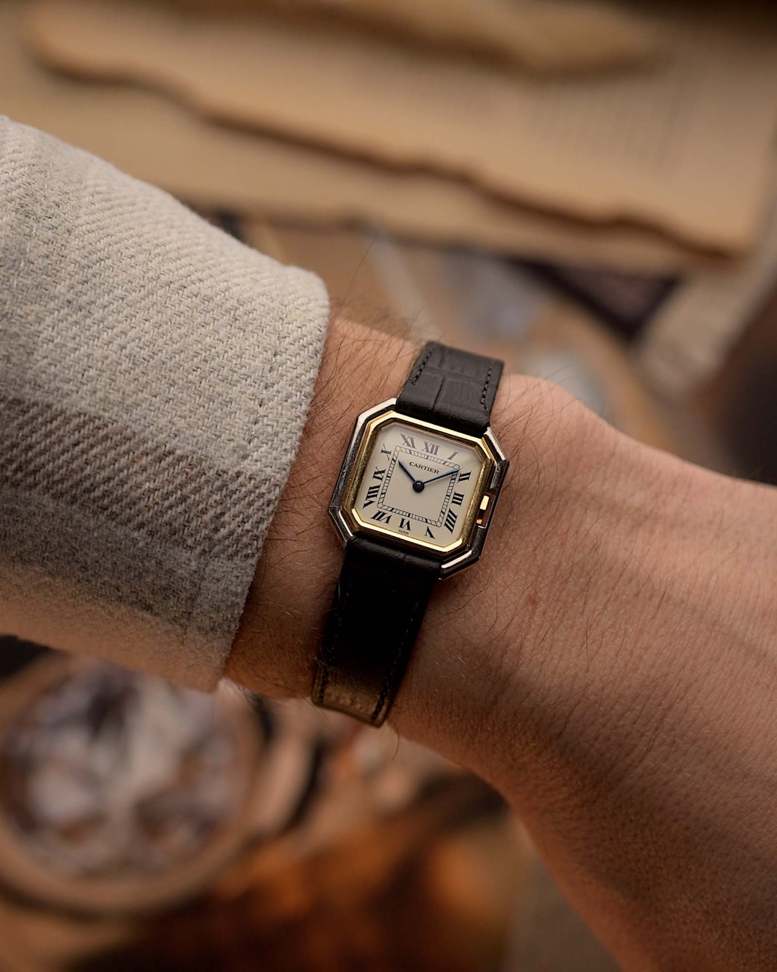 Orologio vintage Cartier Ceinture degli anni '80, oro bicolore, quadrante bianco, cassa quadrata, su un polso su sfondo sfocato.