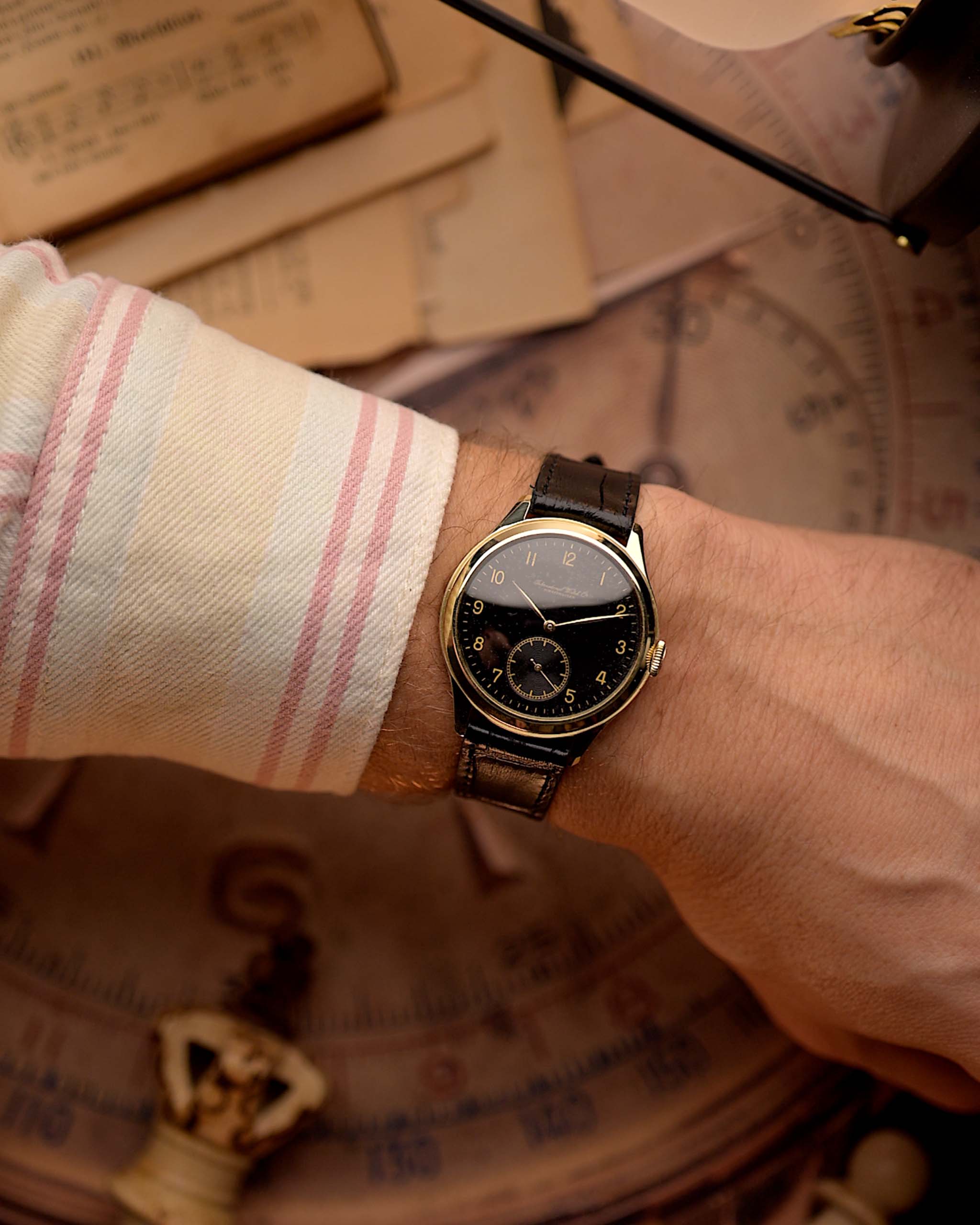 Primo piano di un orologio vintage IWC Pre Hermet, su una superficie sfocata e strutturata