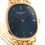 Foto ravvicinata di un Patek Philippe Ellipse 3648 d'Or 18k Blue degli anni Settanta. Cassa da 27 mm in oro giallo con carica manuale Cal. 23-300, quadrante blu a raggiera e bracciale a maglie d'oro integrato.