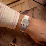 Orologio vintage Piaget TV 9574 con cassa TV in oro bianco 18 carati, quadrante in oro bianco, carica manuale, bracciale integrato su un polso con uno sfondo vintage.