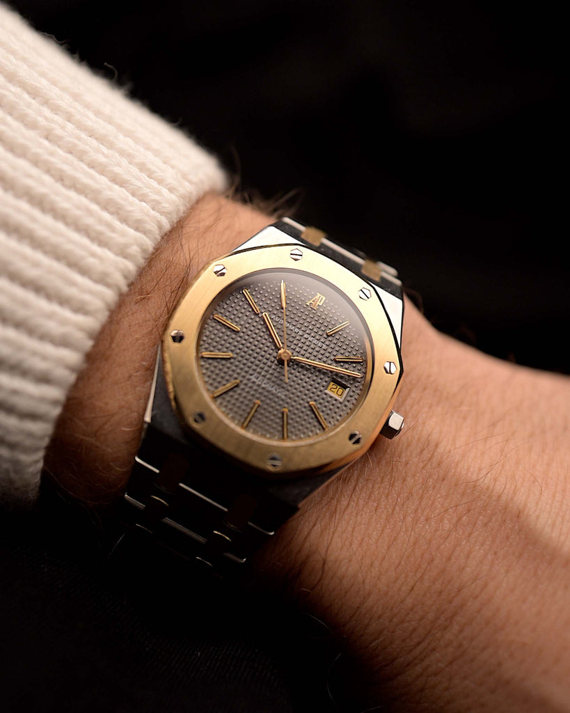 Audemars Piguet Royal Oak 14486SA Vintage Watch from the 1980s on a wrist on black background. 35mm wide in Two-Tone Stainless Steel & Yellow Gold, Automatic movement, Grey tapisserie dial and Two-Tone Bracelet.